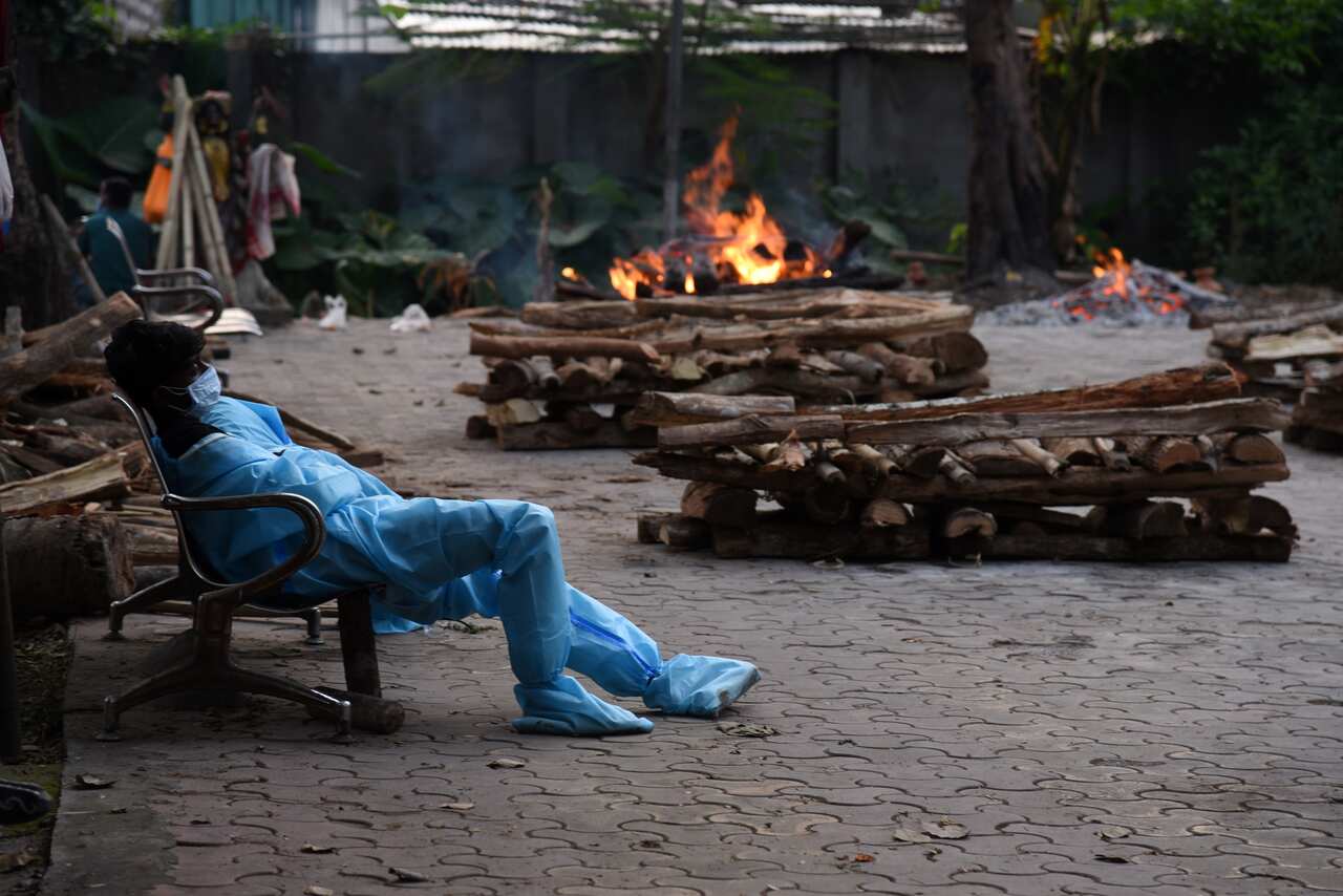 A municipality worker is shown exhausted during the last rites of people who died of the COVID-19 at a crematorium in Guwahati, India on 2 May. 