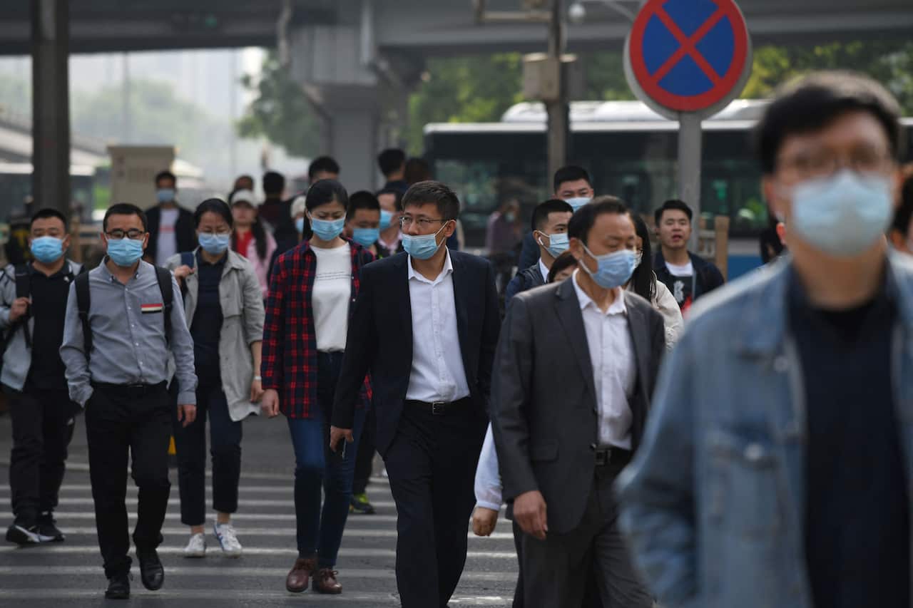 Commuters cross a street during morning rush hour in Beijing on 11 May, 2021.