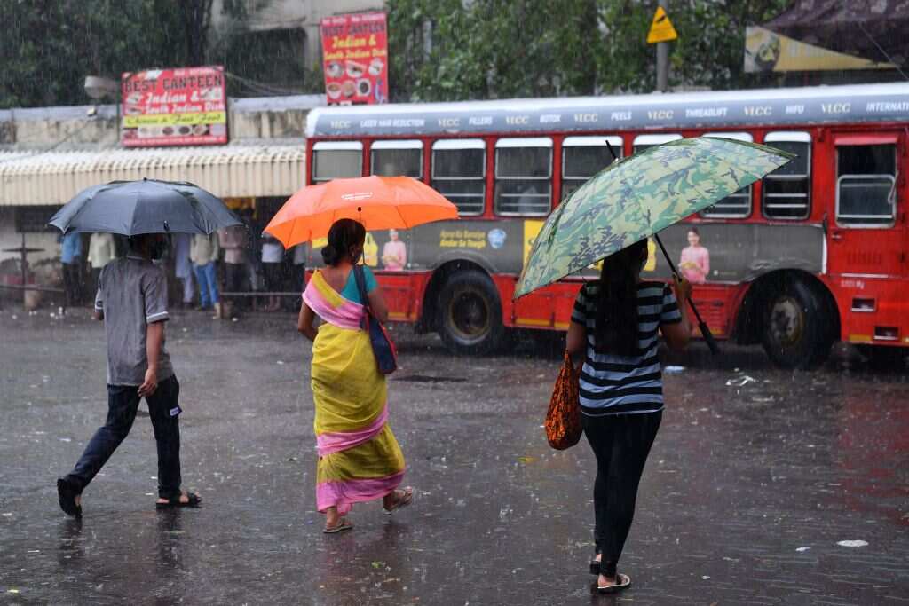 Passengers walk through a street near a bus terminus amidst heavy rains from Cyclone Tauktae in Mumbai on 17 May 17 2021.