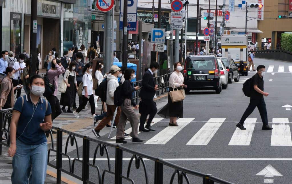 Pedestrians cross a street in Tokyo on May 18, 2021, as Japan's economy contracted 1.3 percent in the three months to March