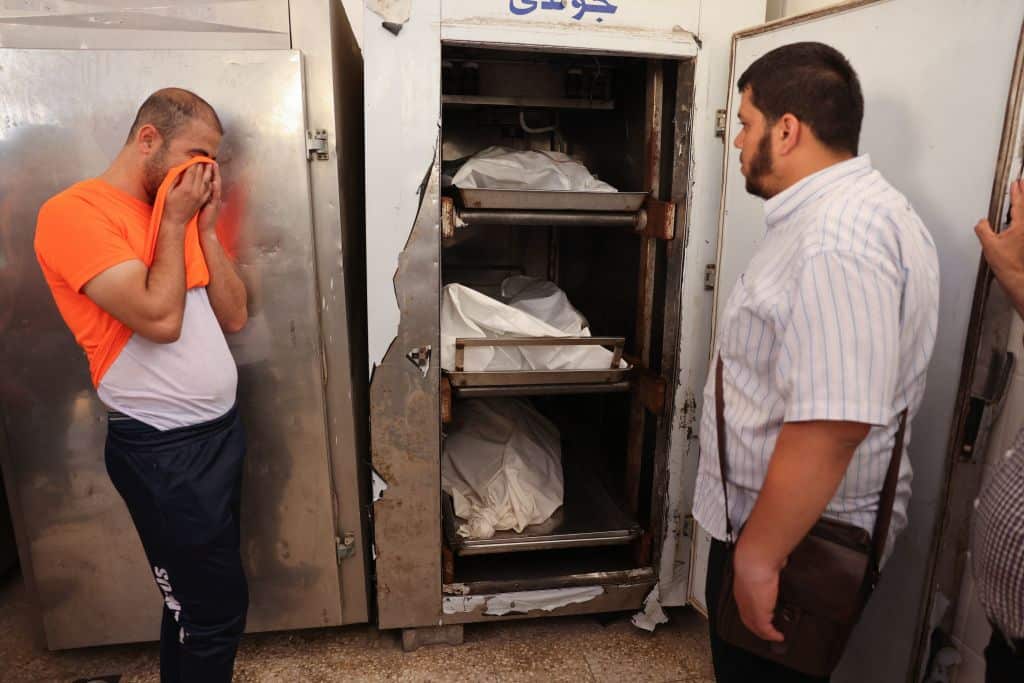 A man weeps in front of the corpses at the morgue after the death of relatives.