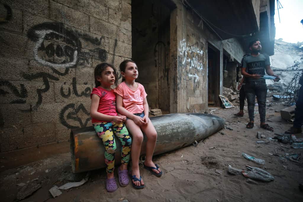 Palestinian kids sit on an unexploded rocket missile thrown by Israeli warplanes on al-Rimal neighbourhood in Gaza City.