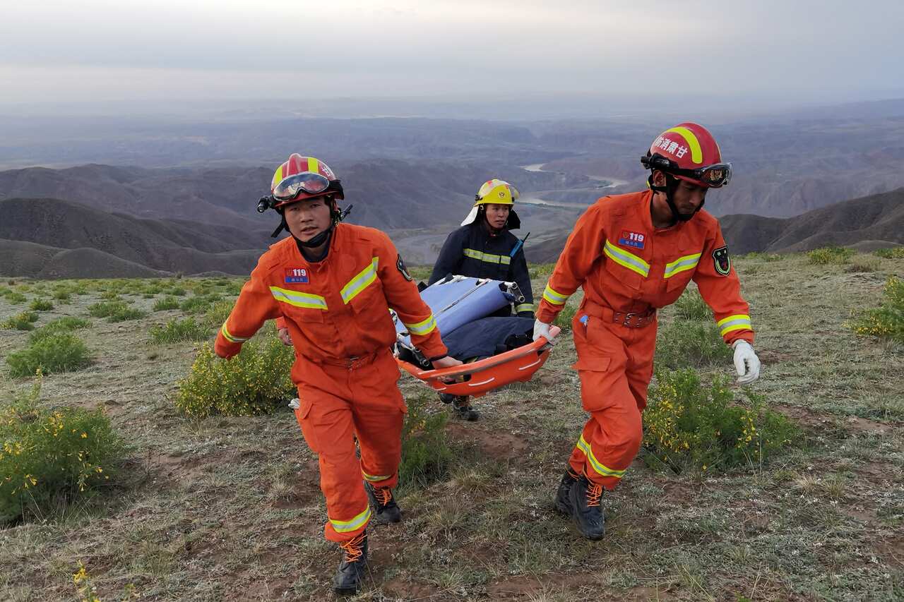Rescuers carry equipment as they search for runners who were competing in a 100-kilometre cross-country mountain race when extreme weather hit the area.