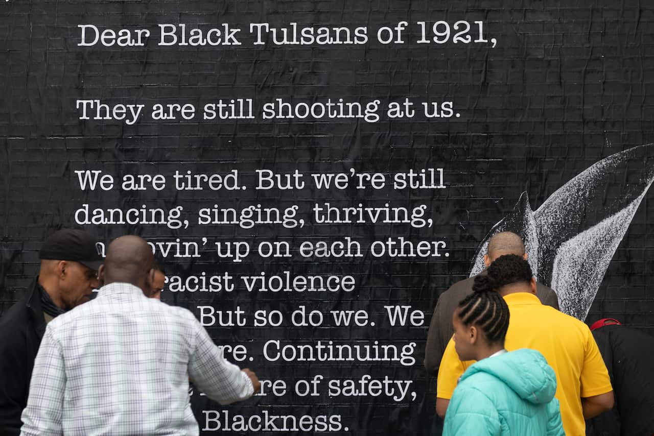 People look at a poster in the Greenwood district on the 100th anniversary of the 1921 Tulsa Massacre in Tulsa, Oklahoma on 1 June.
