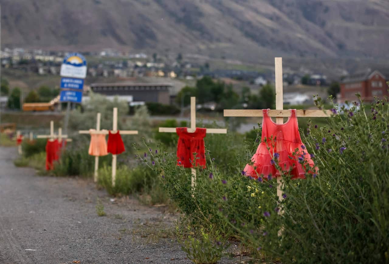 Children's dresses are staked along a highway near the former Kamloops Indian Residential School as part of a growing makeshift memorial.