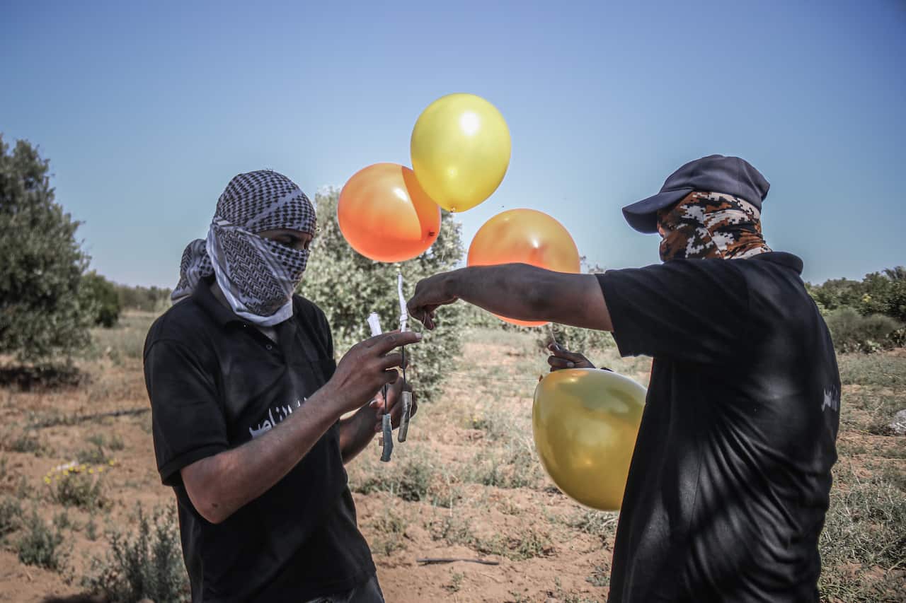Masked supporters of the Al-Nasir Salah Al-Din Brigades prepare incendiary balloons east of Gaza city, to launch across the border fence towards Israel.