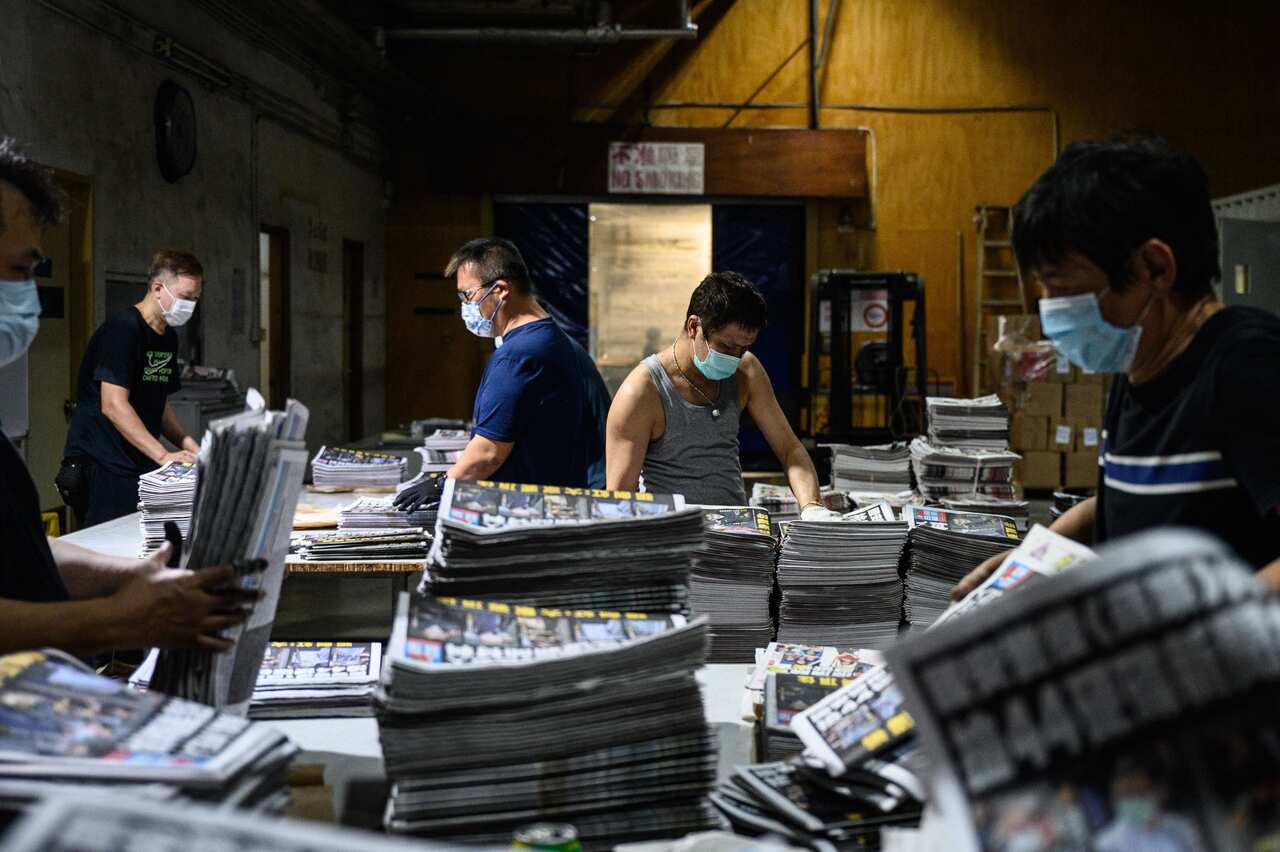 Employees compile freshly printed papers in the printing facility of the Apple Daily newspaper offices in Hong Kong early on 18 June, 2021.