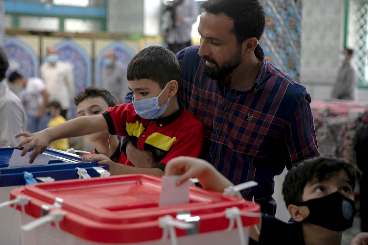 An Iranian voter attends a polling station with a young child to vote during the presidential election in Tehran, Iran, on Friday,  18 June.