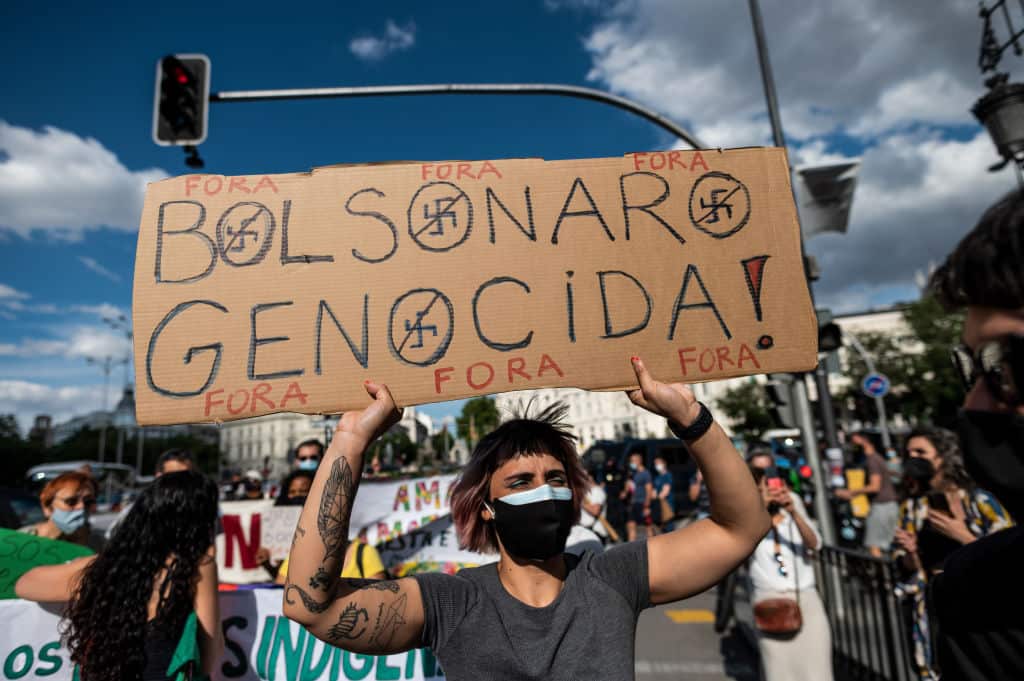 A protester carrying a placard reading 'Bolsonaro genocidal