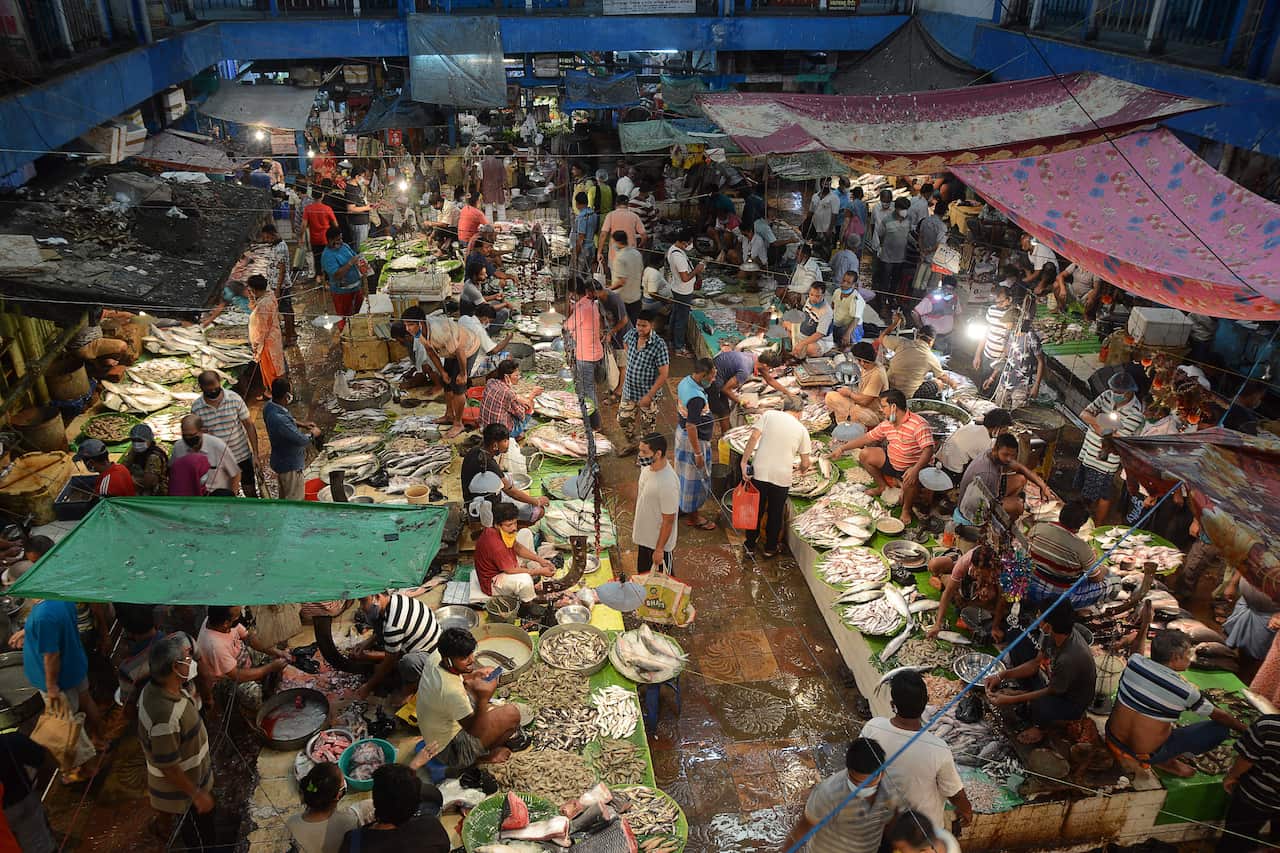 People shop at a fish market in Kolkata on 20 June, 2021 after West Bengal's state government eased lockdown restrictions to curb the spread of the COVID-19.