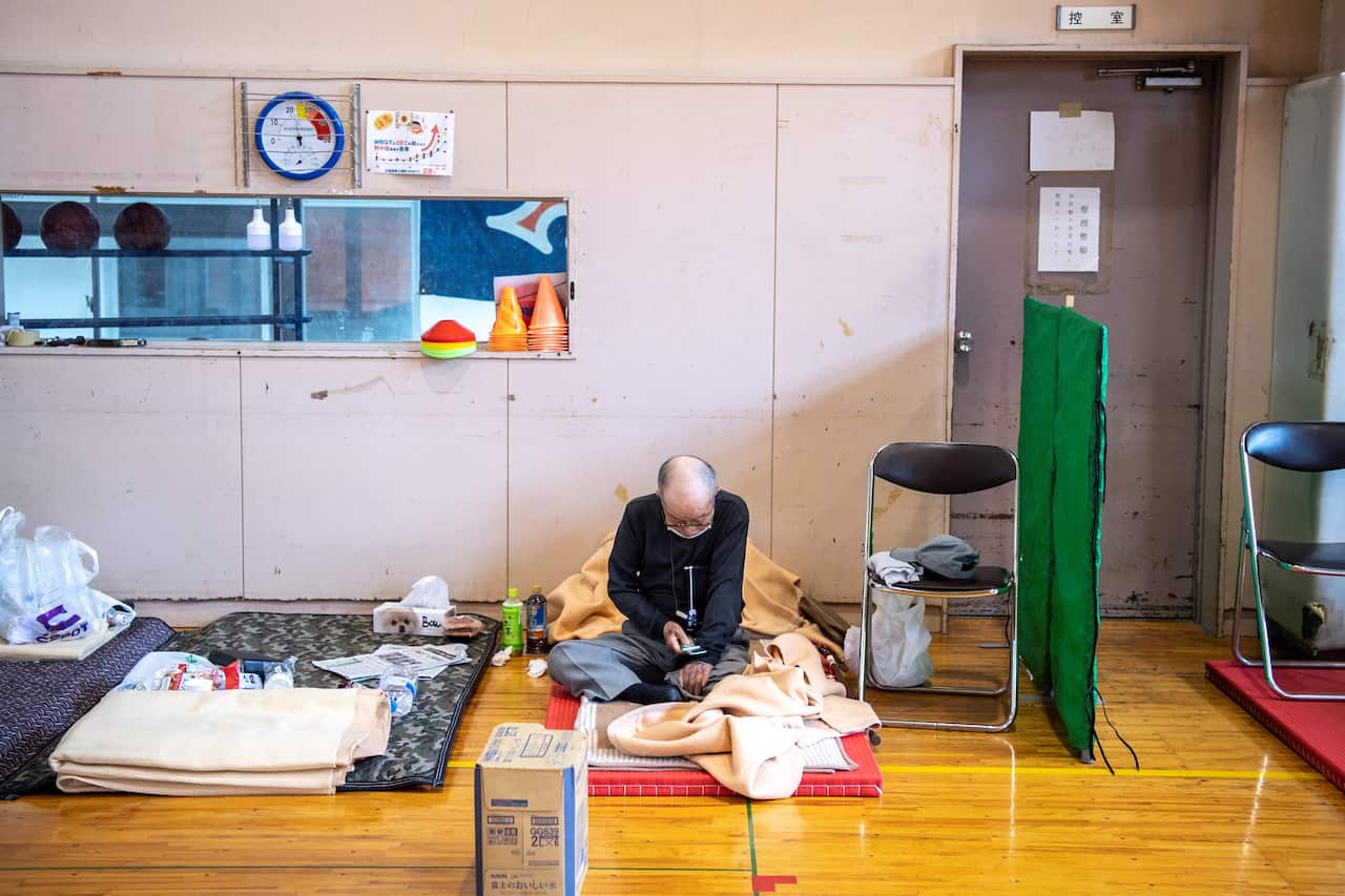 A landslide-affected resident sits in an evacuation centre following days of heavy rain in Atami in Shizuoka Prefecture on 4 July 2021.