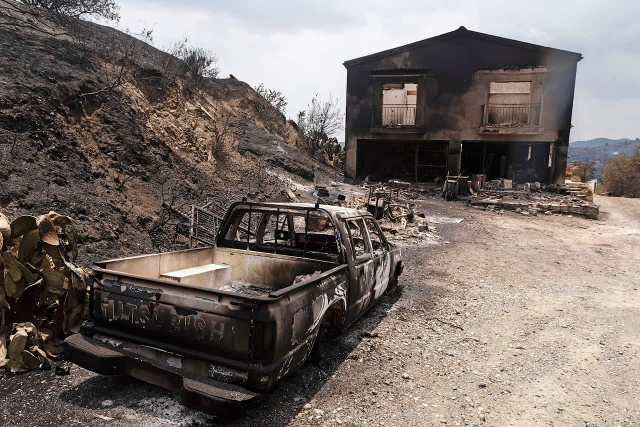 A picture taken on 4 July, 2021 shows a burnt car and house near Ora village on the southern slopes of the Troodos mountains in Cyprus. 