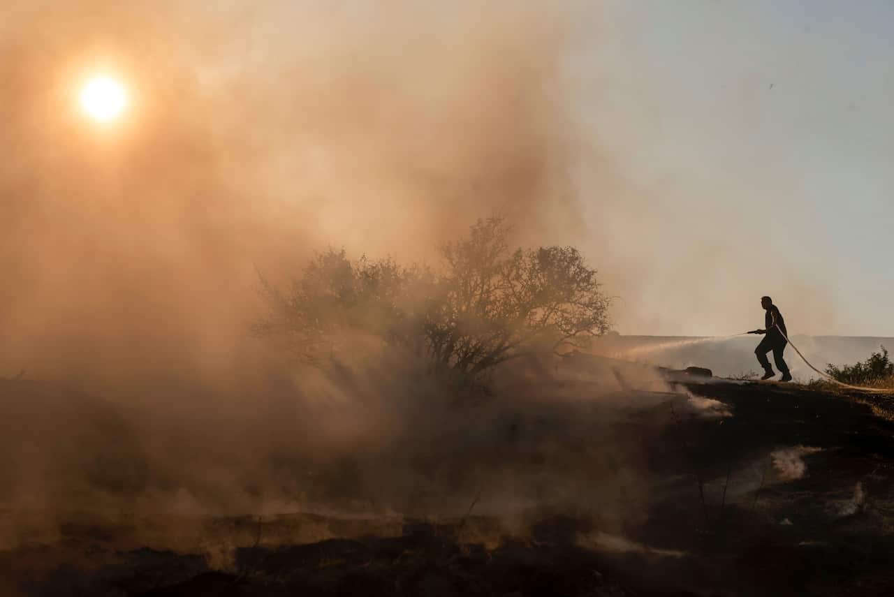 A firefighter douses the flames in an effort to contain a fire on the outskirts of Cyprus' capital Nicosia on 4 July, 2021. 