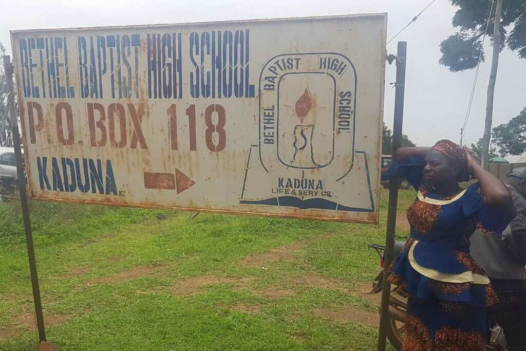 Parents stand beside the signpost of Bethel Baptist School where around 140 boarding students were kidnapped by bandits in Kaduna, Nigeria on 5 July 2021.