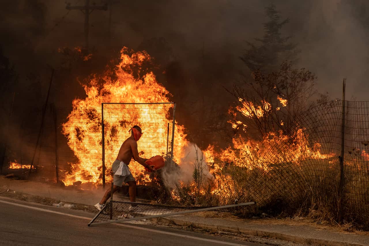 A volunteer tries to put out the fire by throwing dirt on it in Athens, Greece on 6 August, 2021. 