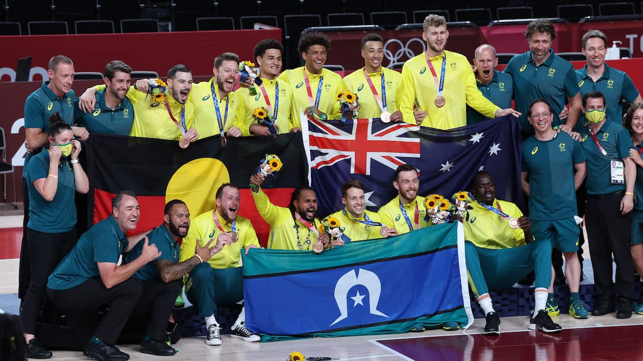 The Australian team poses for pictures on the podium after receiving their bronze medals in the men's basketball competition of the Tokyo Olympic Games. 