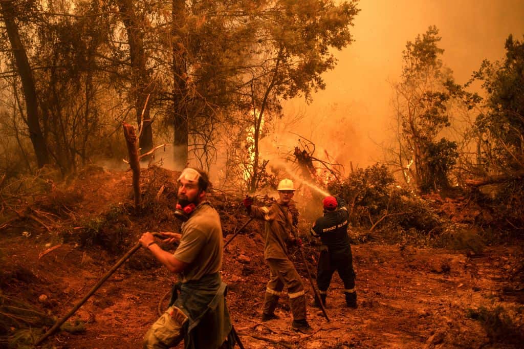 A firefighter gestures as he and volunteers use a water hose near a burning blaze in the village of Glatsona on Evia island, on 9 August, 2021.