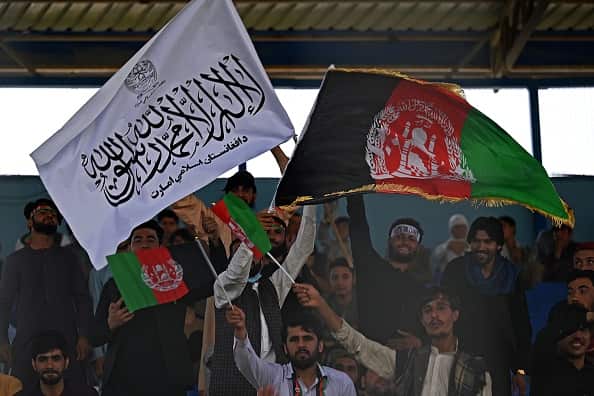 Spectators wave Afghanistan's and Taliban flags as they watch a Twenty20 cricket match in Kabul on 4 September 2021.