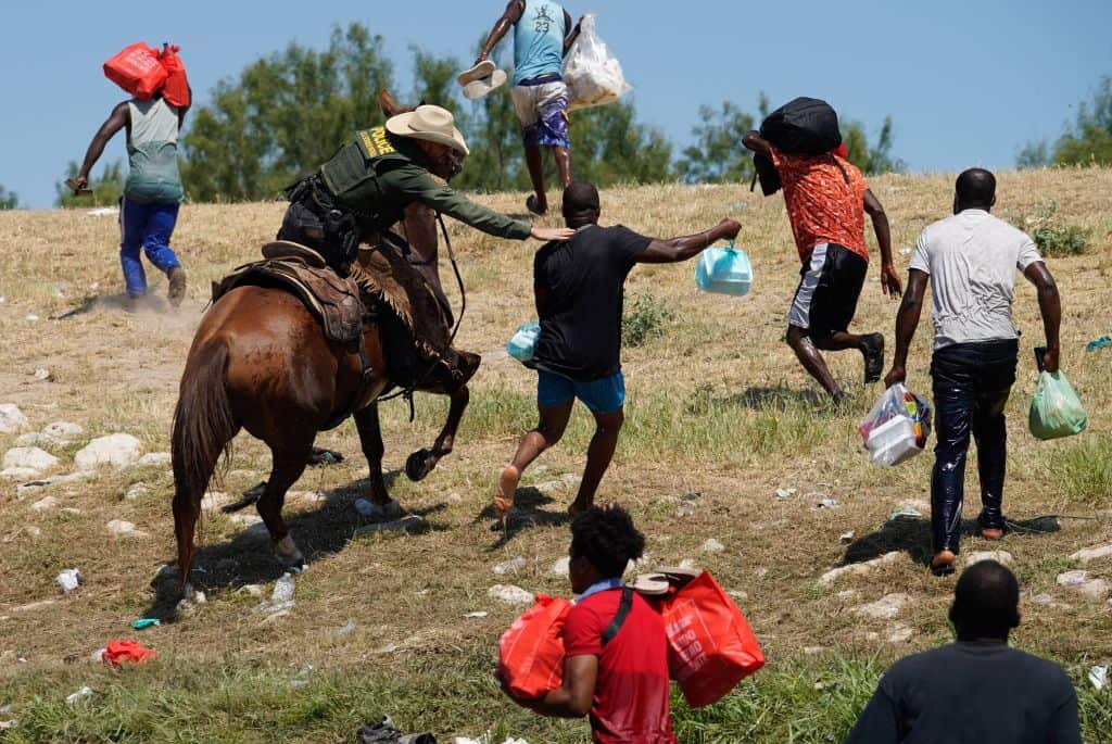 A United States Border Patrol agent on horseback tries to stop a Haitian migrant from entering an encampment