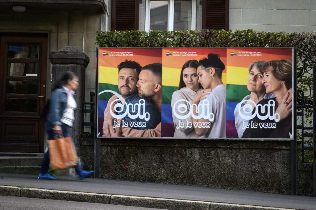 A woman walks past an electoral poster reading in French: "Yes I want it" ahead of a nationwide vote on same-sex marriage on September 22, 2021 in Lausanne, Switzerland.