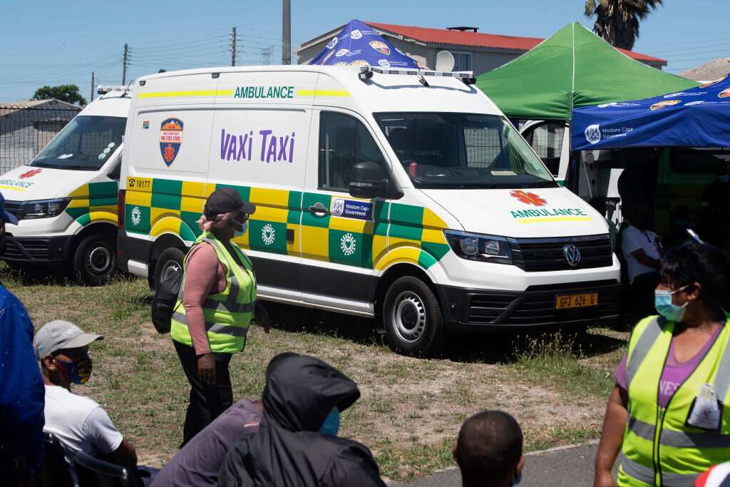 People wait to get vaccinated outside an ambulance which has been converted to facilitate vaccinations at a COVID-19 vaccination evenn Cape Town