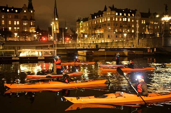 Kayakers during a night paddle on a river in Stockholm, Sweden.
