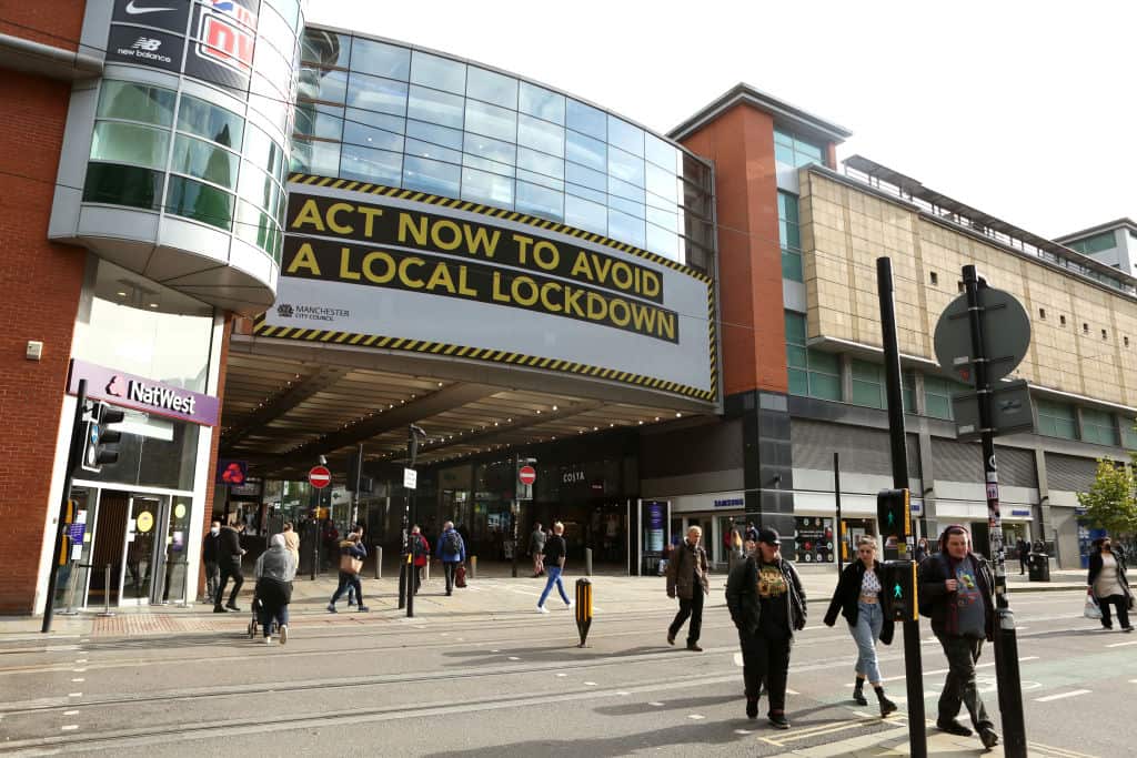 People both with and without face masks are seen walking through Manchester, England.