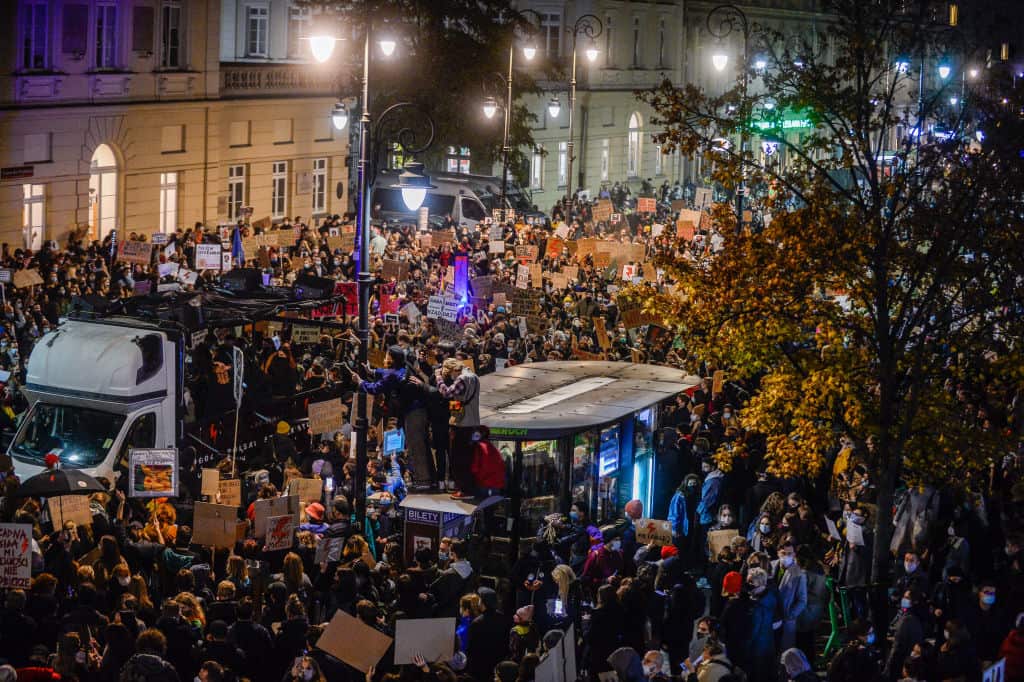 People hold banners and dance as they participate in a national strike during the seventh day of protests in Warsaw. 