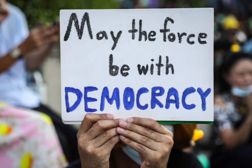 A protester holds up a message outside the headquarters of the Siam Commercial Bank in Bangkok, Thailand.