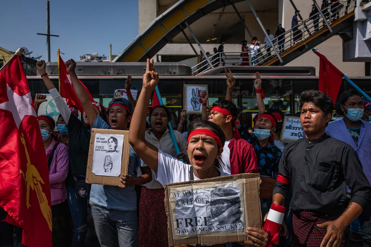Protesters hold placards and shout slogans near the City Hall on 13 February, 2021 in Yangon, Myanmar.