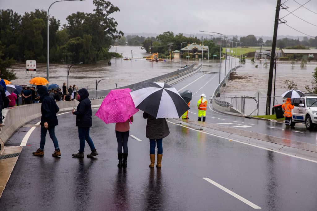 People look on as flood water rises over the New Windsor Bridge on The Hawkesbury River in Windsor on 21 March in Sydney, Australia.