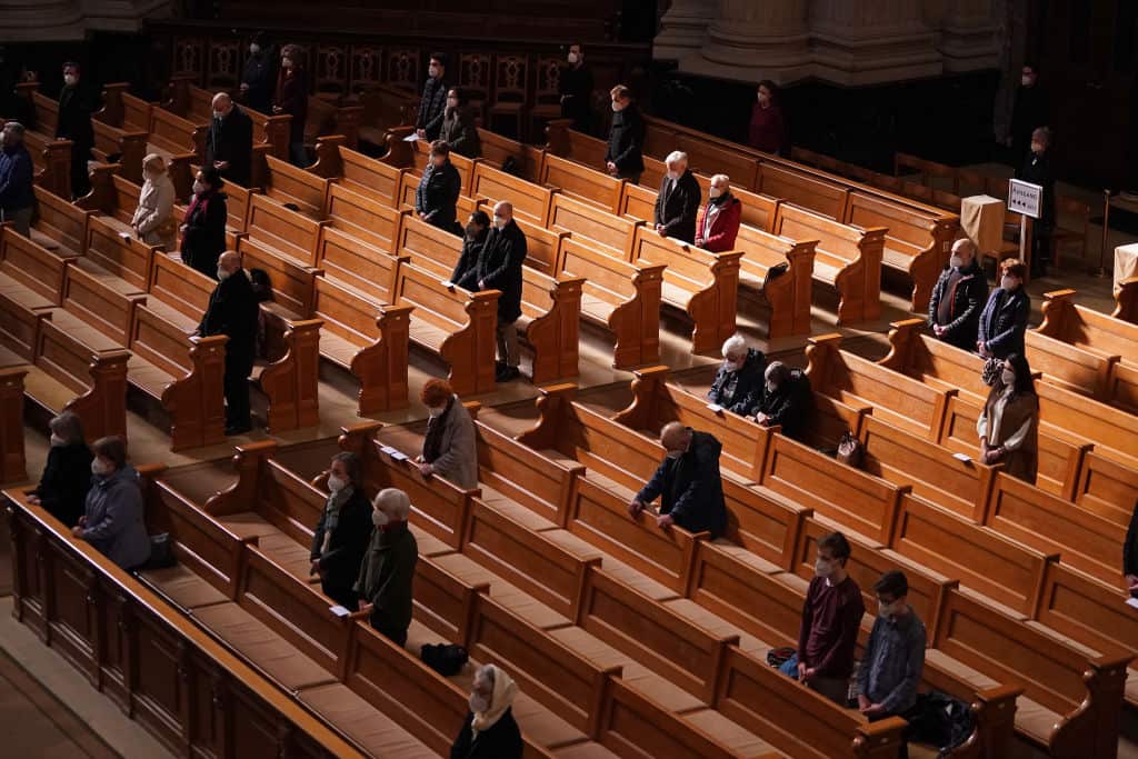 People wear face masks and stand spaced far apart as they attend a Good Friday religious service at the Protestant Berlin Cathedral on 2 April, 2021. 