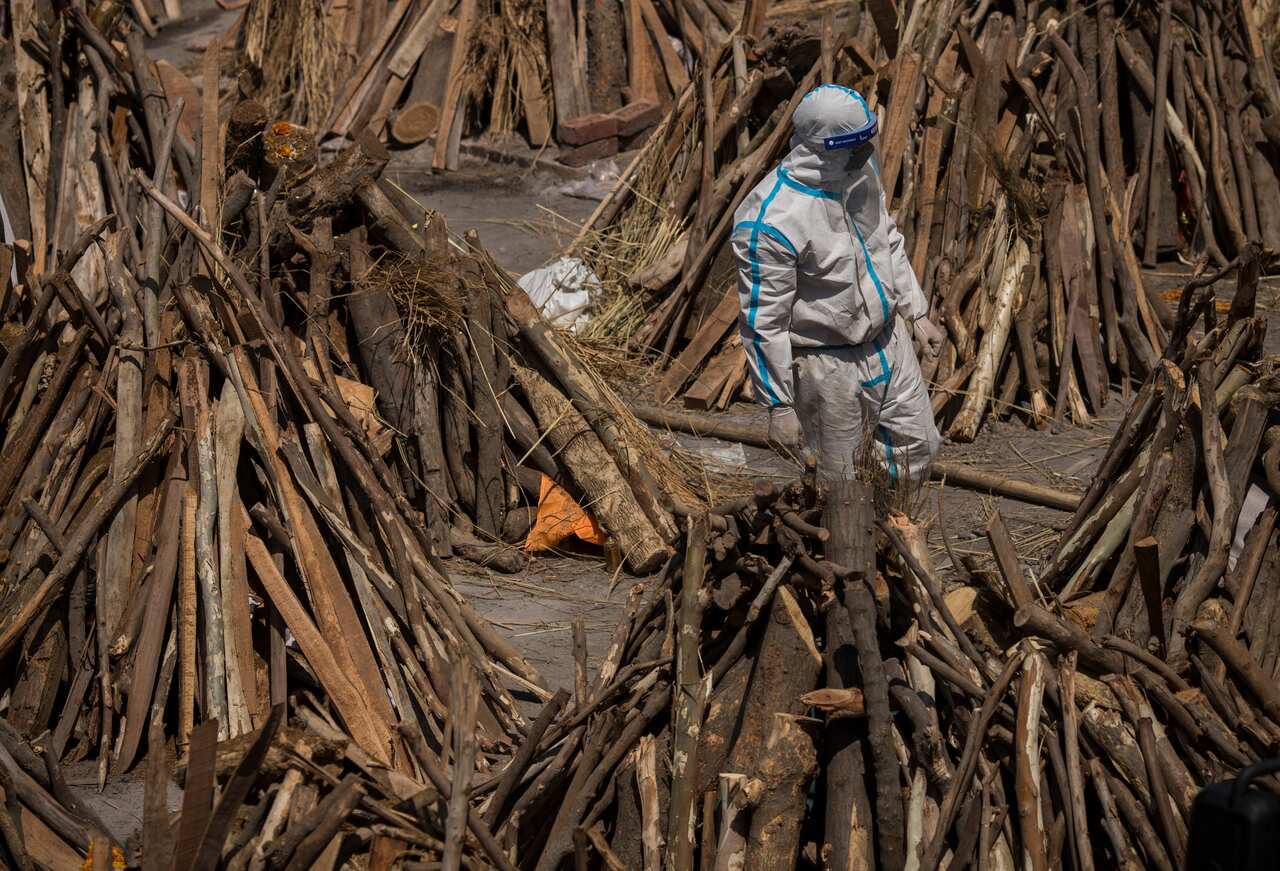 A man  is seen amid funeral pyres before they are lit to perform the last rites of patients who died of COVID-19, at a New Delhi crematorium on 24 April.