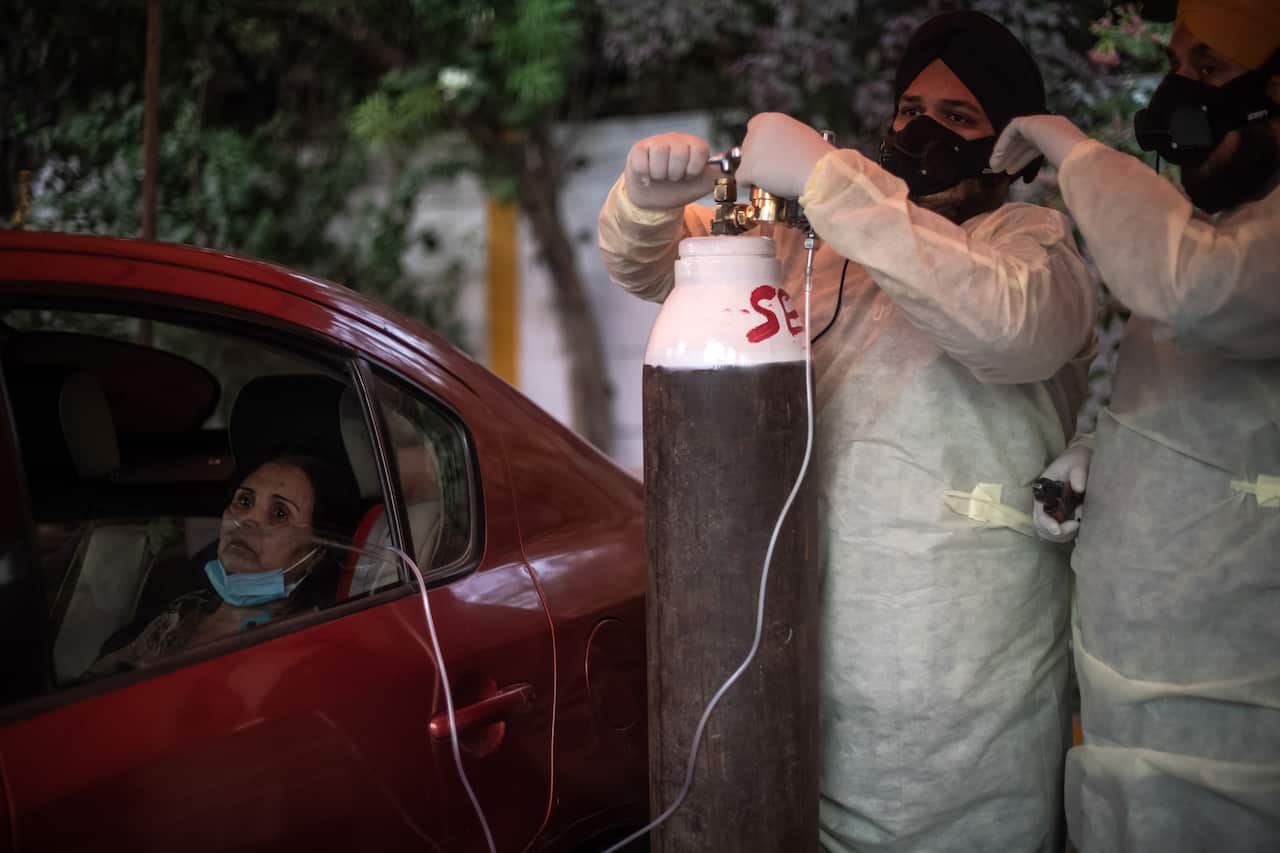COVID-19 patient Adila Ebadi, 58, is treated by volunteers at a makeshift clinic providing free oxygen outside Gurdwara Damdama Sahib in New Delhi on 3 May.