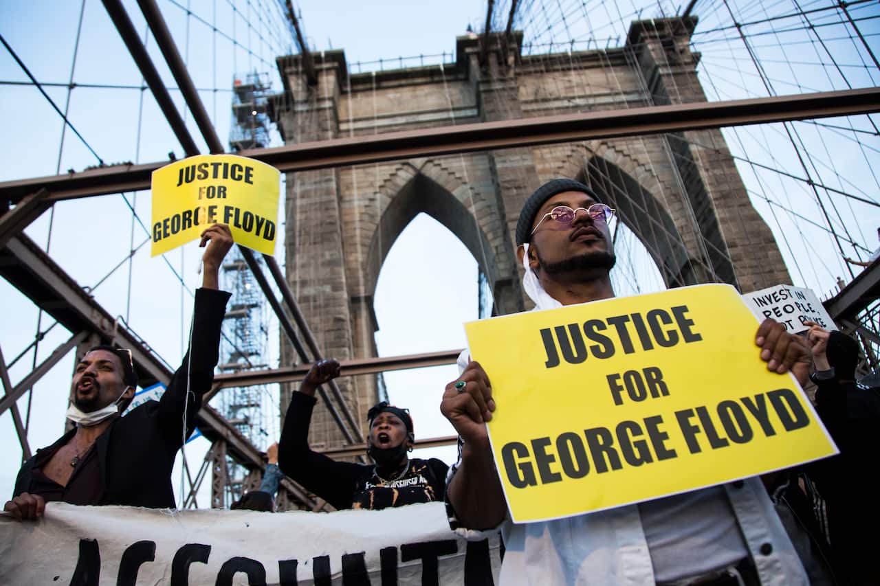 Black Lives Matter supporters hold placards on the Brooklyn Bridge on the first anniversary of George Floyd's death on 25 May, 2021 in New York City. 