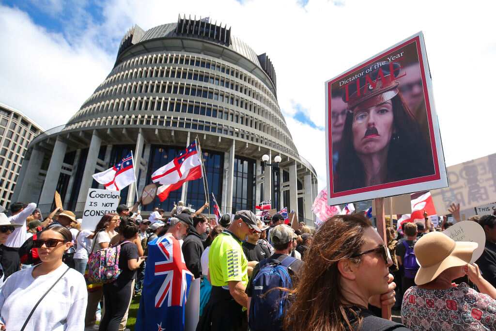 A protester holds a sign displaying the image of Prime Minister Jacinda Ardern 