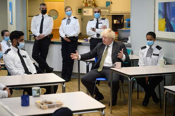 UK Prime Minister Boris Johnson sitting at a table and talking to police at Uxbridge police station on 17 December.