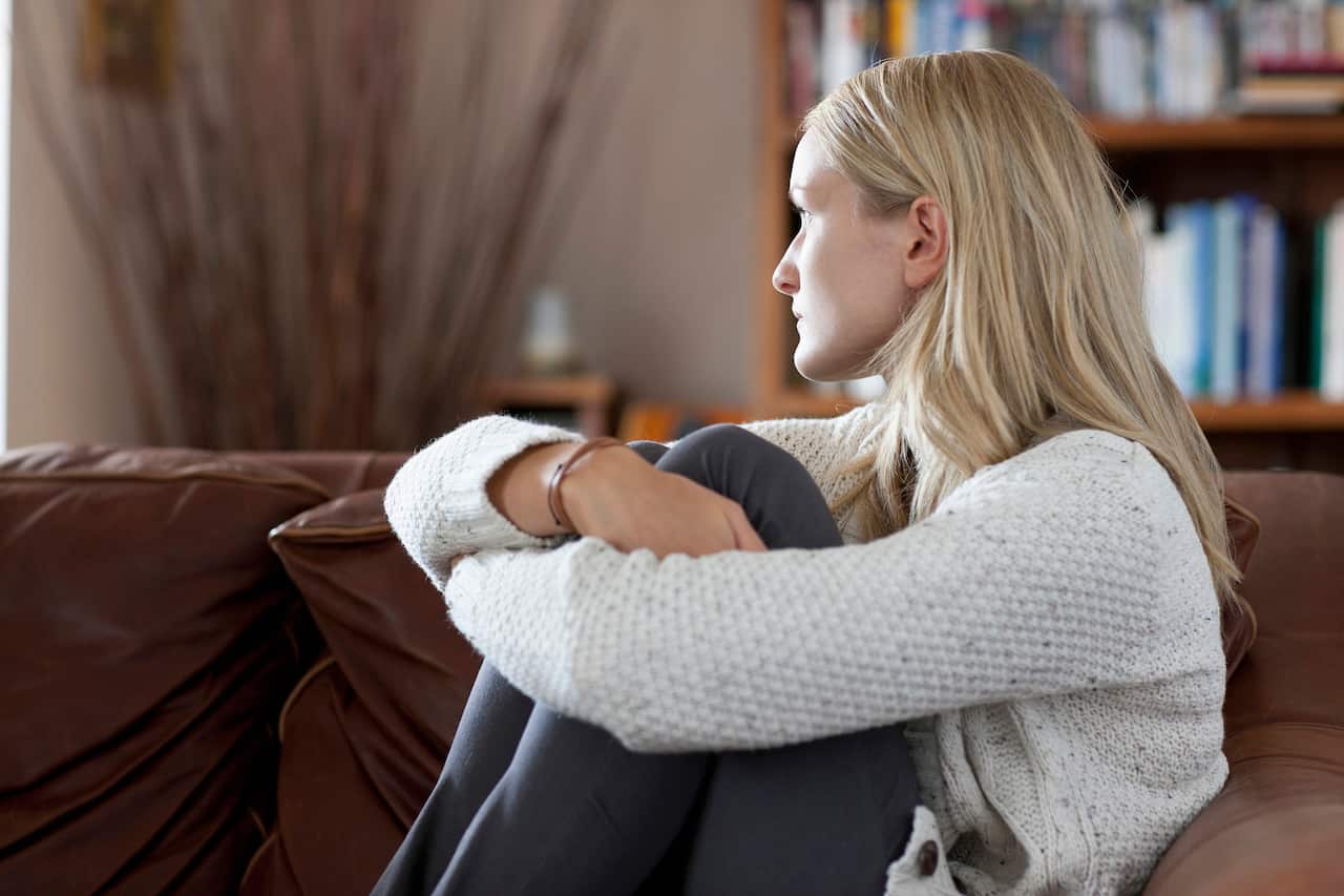 Anxious woman sitting in sofa daydreaming