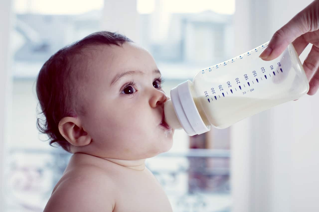 Infant drinking milk from baby bottle