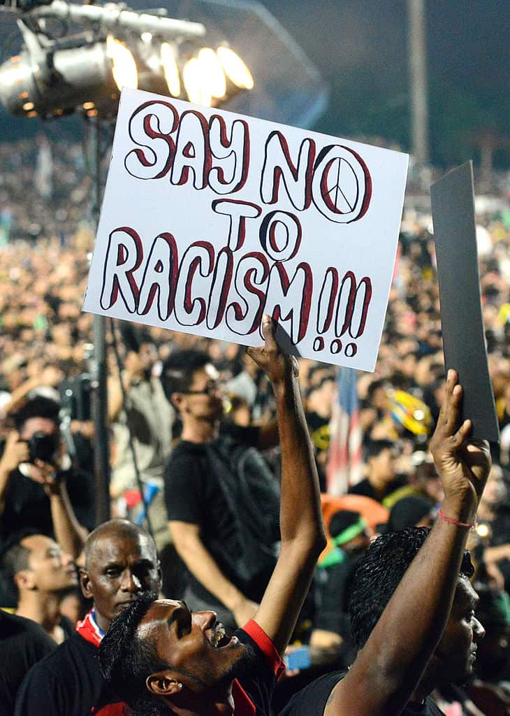 A supporter holds up a sign against racism as opposition leader Anwar Ibrahim speaks at a football stadium in a gathering in Kelana Jaya on May 8, 2013. 