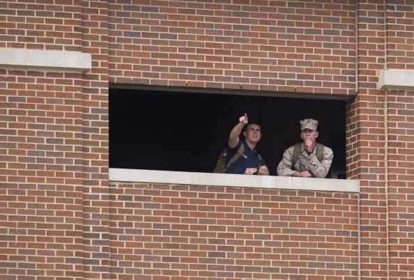 Members of the military look out from a nearby building toward police units responding to a shooting at the Navy Yard in Washington, DC, September 16, 2013.