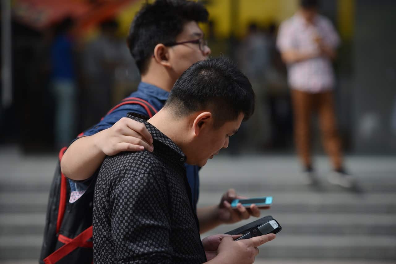 People use their mobile devices on a street in Shanghai.