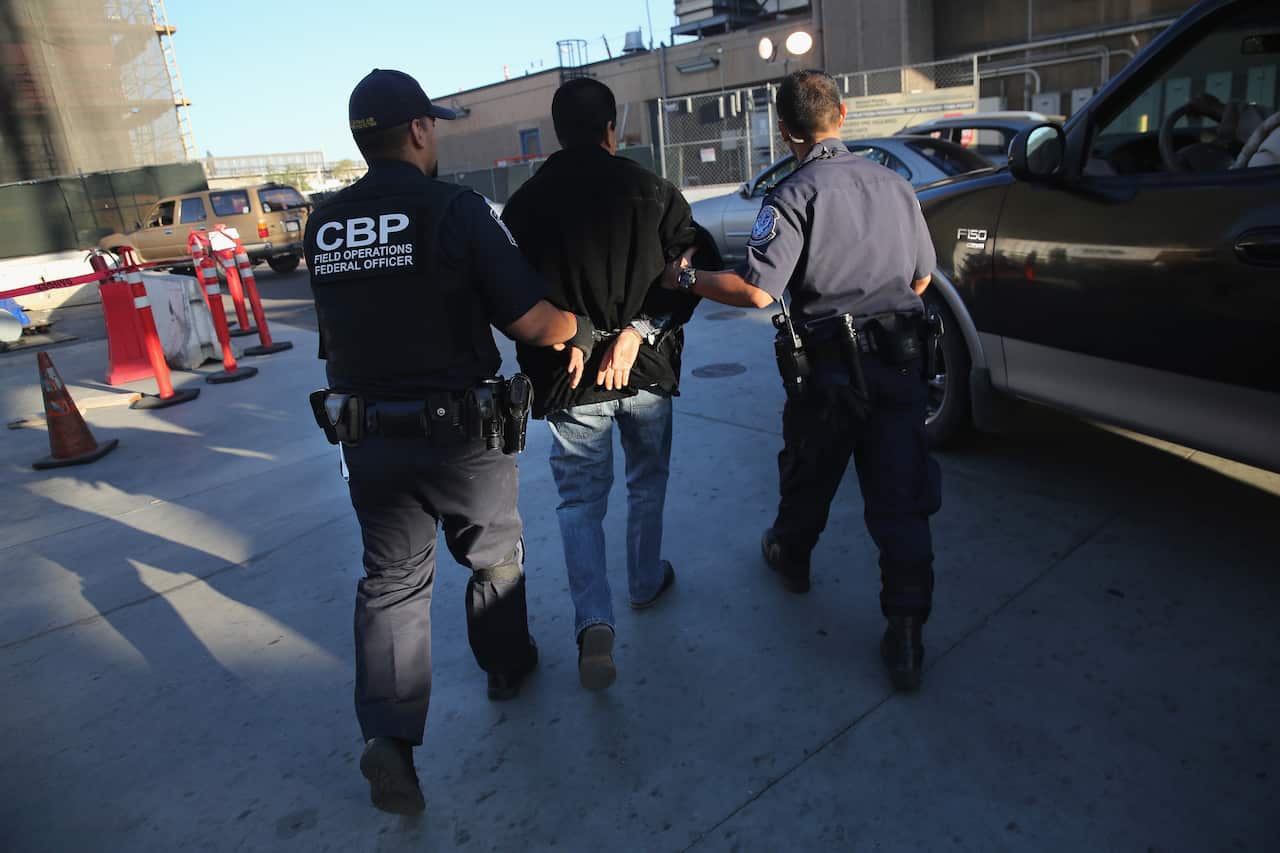 US Customs And Border Protection officers take a man in for questioning.