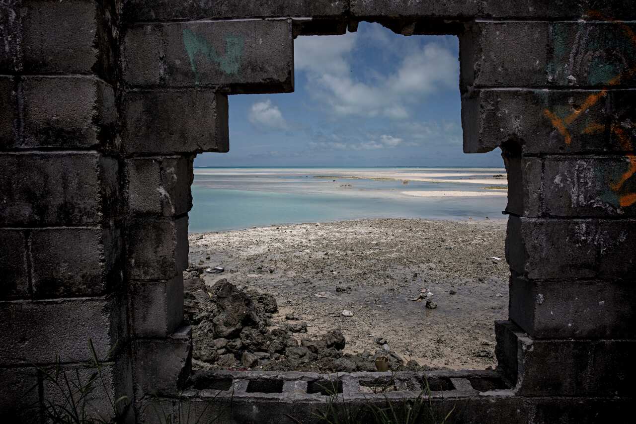 An exposed seabed viewed through a hole in a wall on an island in Kiribati.