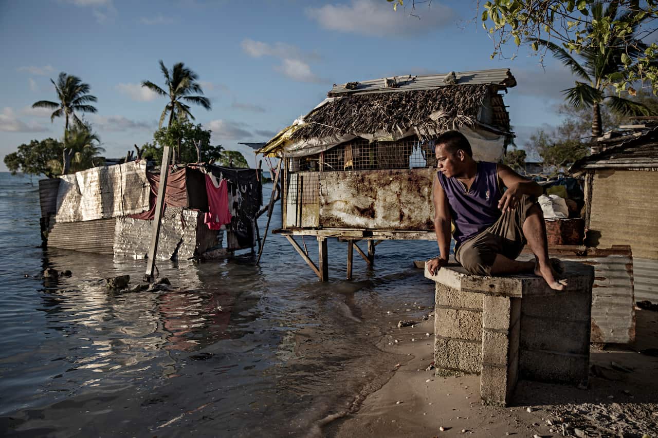 One of the residents of the village Eita is sitting and watching the ocean water slowly flood his village.