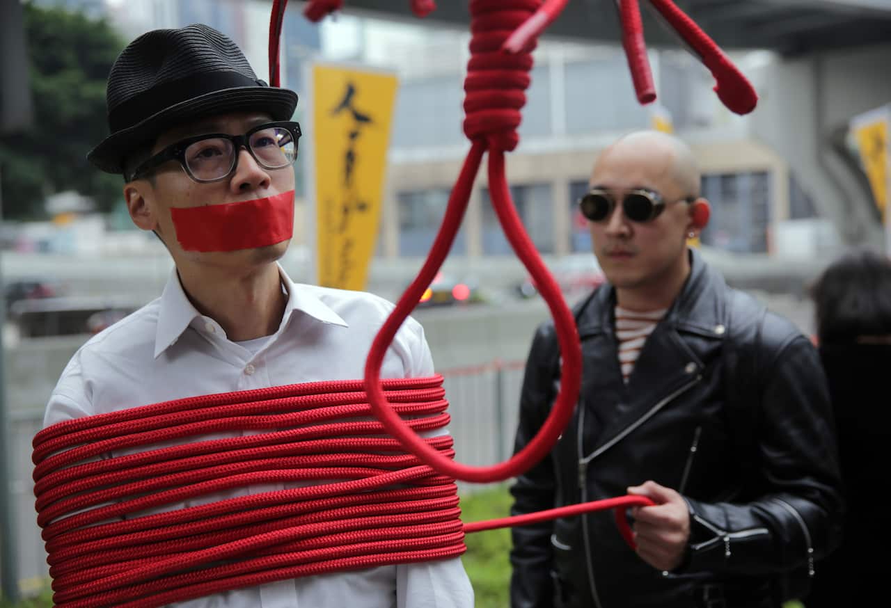 A protester is wrapped up with a rope made into a noose during a march calling for the release of missing booksellers from Hong Kong's Mighty Current publisher.