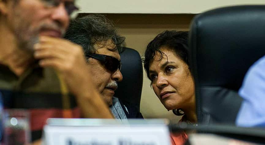 two FARC negotiators in discussion during a press conference.