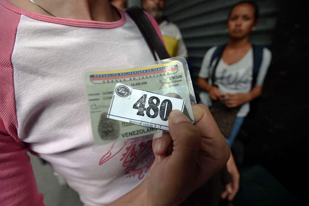 A woman holding a number to buy food waits outside a supermarket in Caracas, Venezuela.