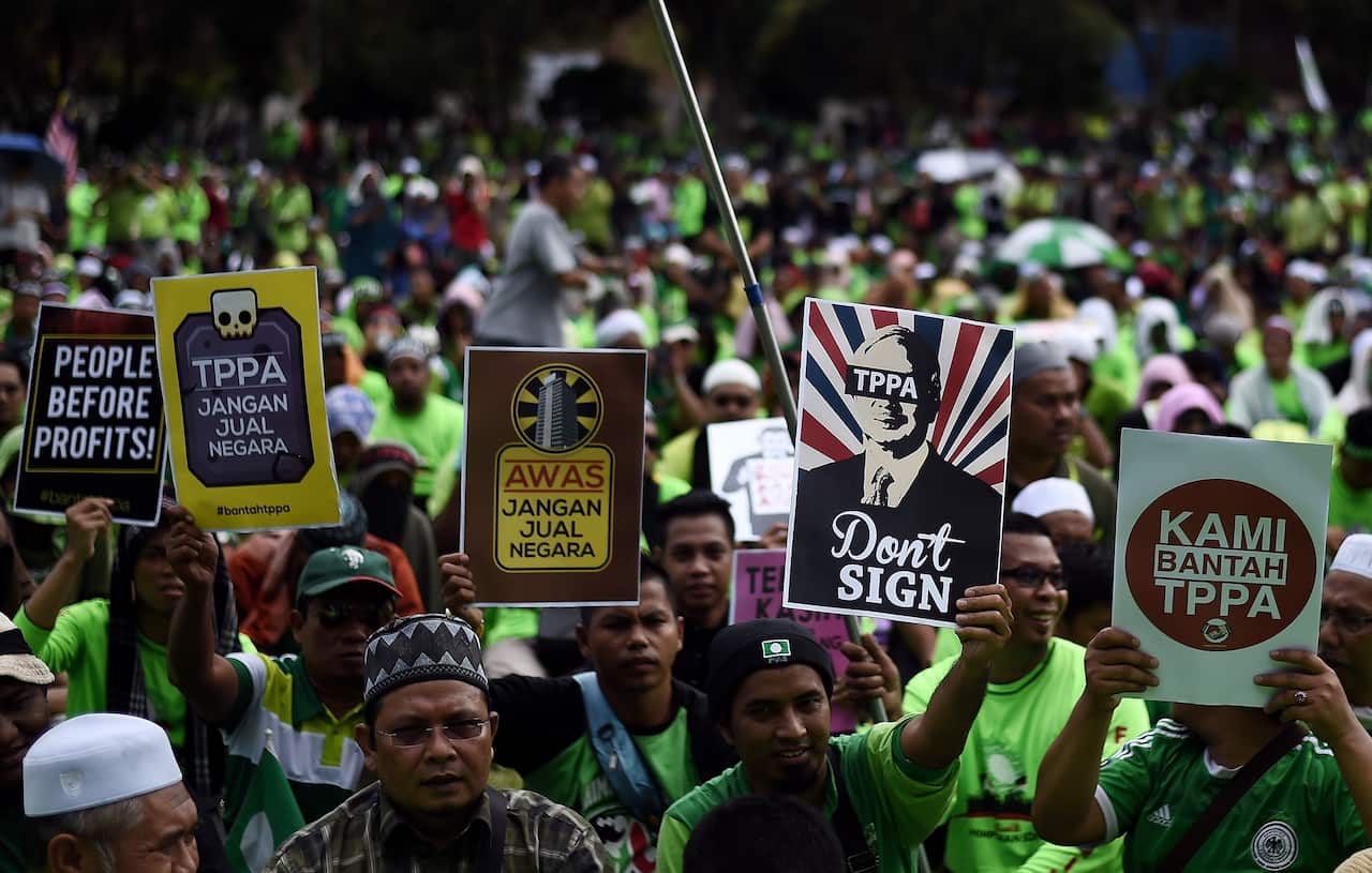 Malaysian activists hold placards denouncing TPP