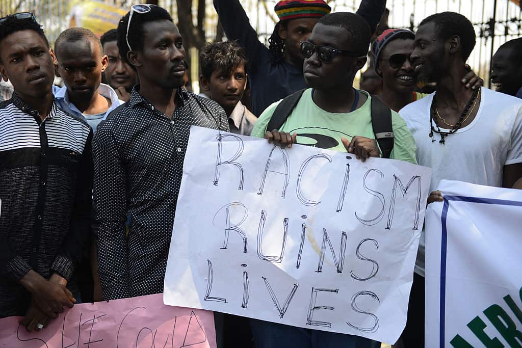 African students protest, a sign reads 'racism ruins lives'